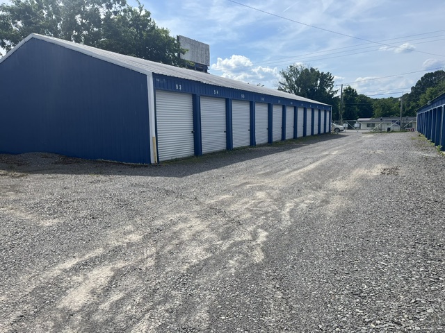 Angled view of a blue storage building with a gravel driveway