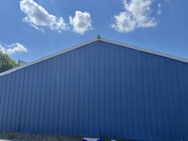 Blue metal storage building against a bright blue sky