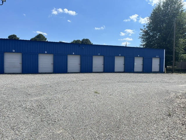 Front row of blue drive-up storage units with white roll-up doors